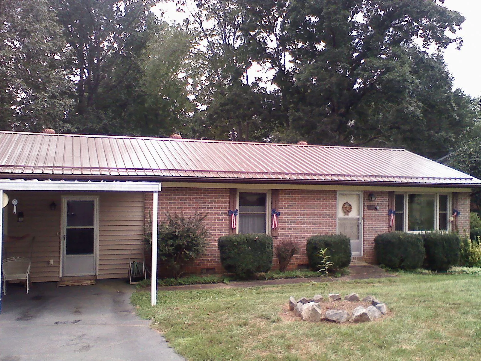 Bronze metal roof and carport on a brick ranch home — Roof Repair work by our crew in Newton